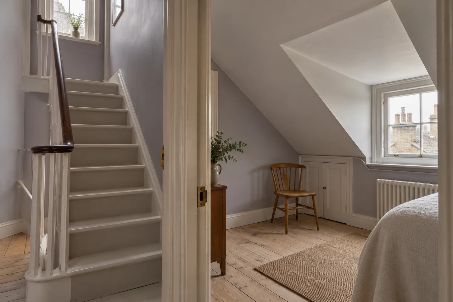 Narrow painted staircase beside a pale top-floor room with a sloping ceiling